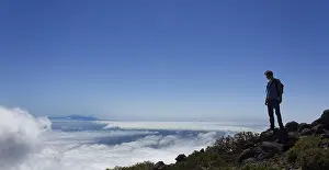 Panoramic Mountain View Stampe: Young man looking across a layer of clouds