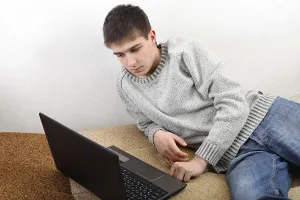 Young Man On Sofa Stampe: Young man with notebook on sofa