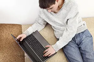 Young Man On Sofa Stampe: Young man with notebook on sofa